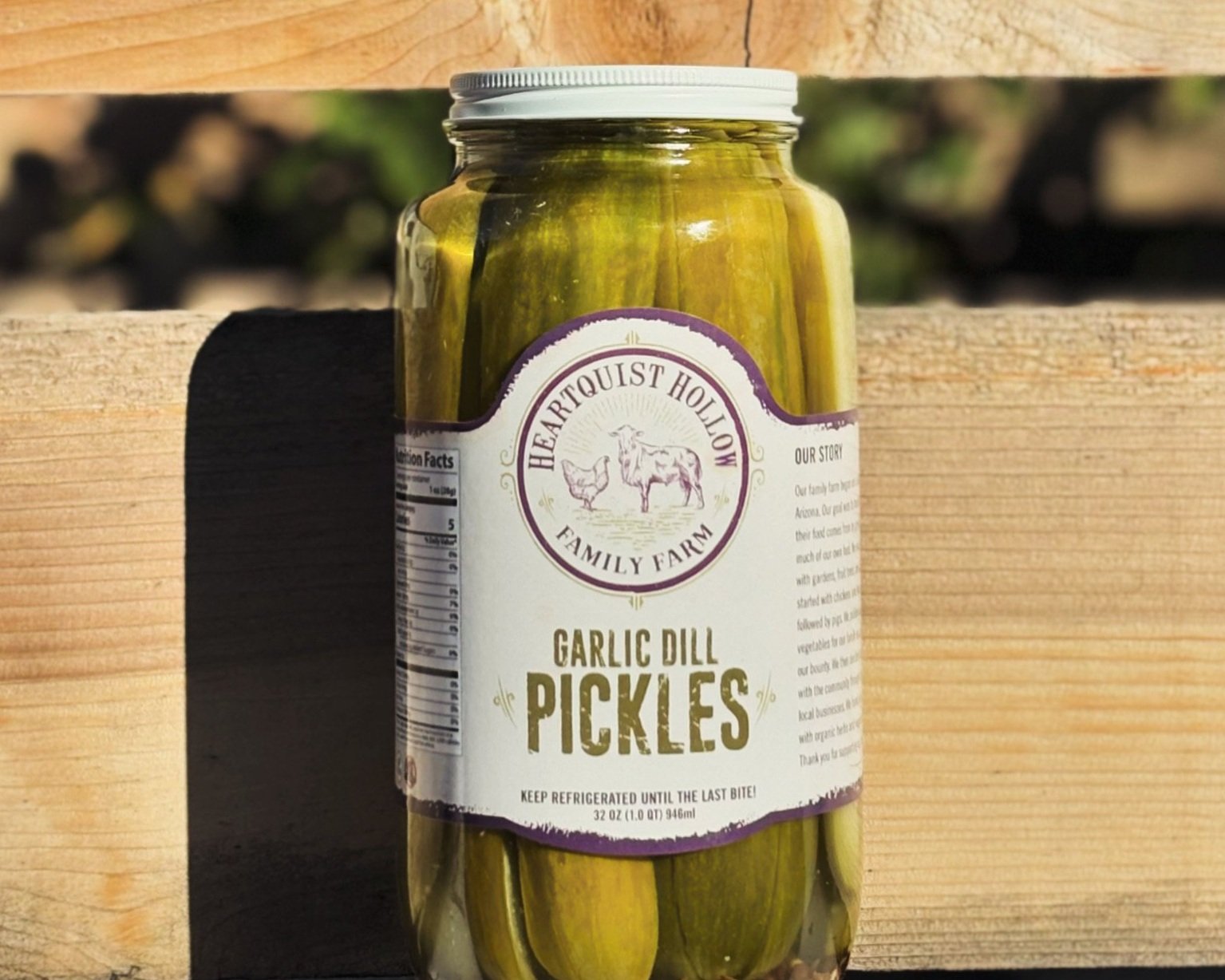 Jar of Heartquist Hollow Garlic Dill Pickles on a wooden surface, showcasing the label and ingredients. Ideal for adding flavor to sandwiches or enjoying as a snack. 32 oz jar, made with fresh cucumbers and garlic, perfect for pickle lovers.
